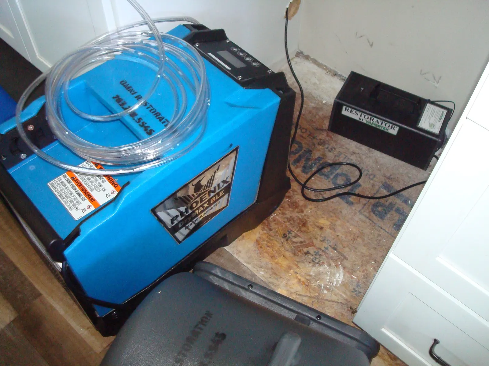 Water damage drying equipment beside a dishwasher after a leak